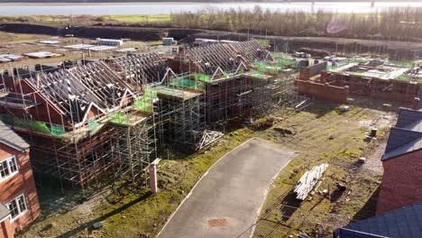 aerial view orbiting unfinished waterfront townhouse scaffolding framework on property development site