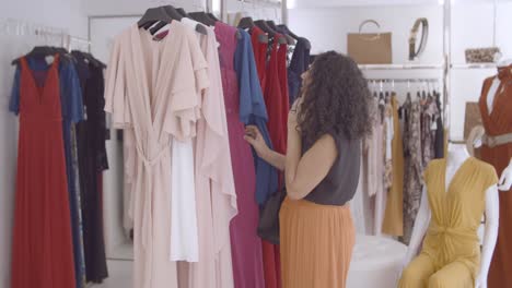 latin woman talking on cell while choosing clothes