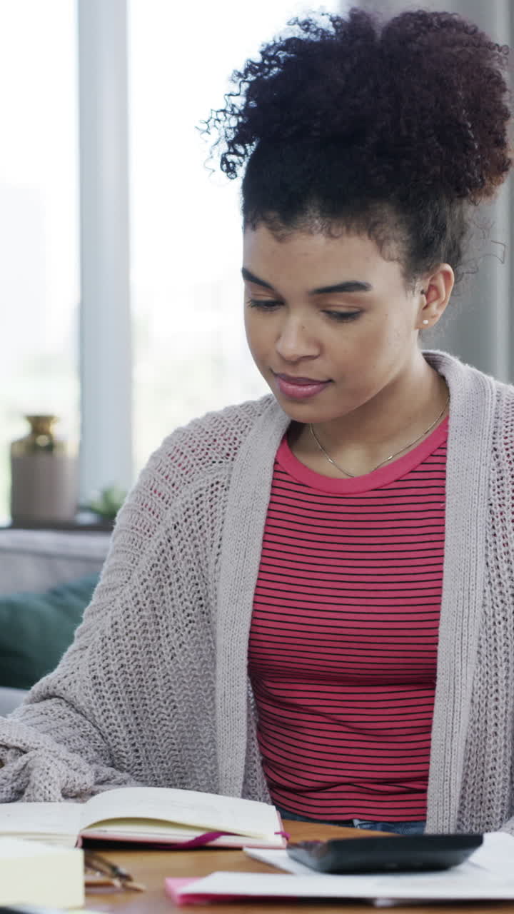 Young Woman Calculating Finances and Writing in Notebook at Home