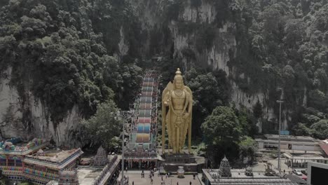 drone shot of. the huge buddha by batu caves in malaysia. shot shows a forward motion of the drown, about 200ft above the crowd.