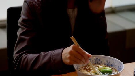 mujer comiendo fideos en un restaurante de 4k