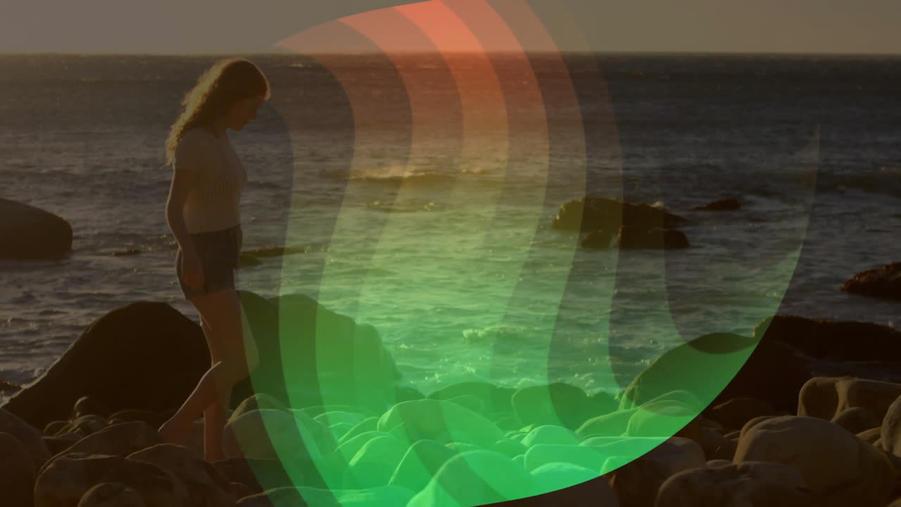 Woman walking on rocky beach with colorful wave animation over ocean