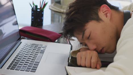 asian male teenager with headphones sleeping and using laptop in living room