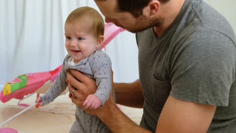 Father-holding-his-baby-boy-while-sitting-on-sofa-4k