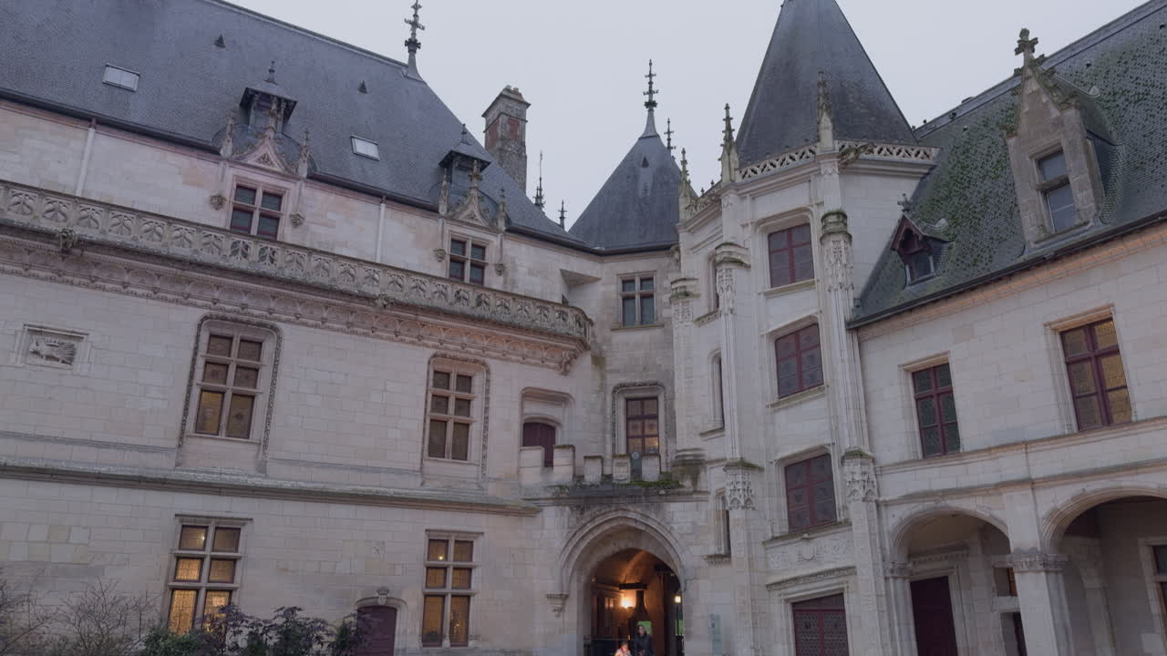Child runs by entrance of Château de Chaumont in France on cloudy day, tilt down