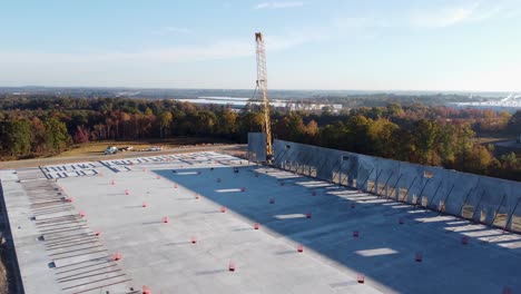 a medium drone shot of a heavy-duty crane swinging a concrete panel into place with braces attached