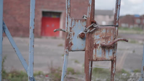 a close up panning shot of a rusty gate on an abandoned industrial site