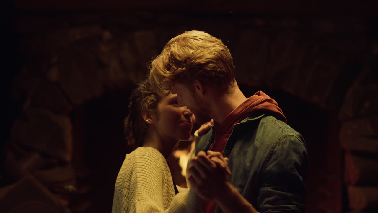 los amantes felices bailan junto a la acogedora chimenea navideña. pareja relajarse en casa