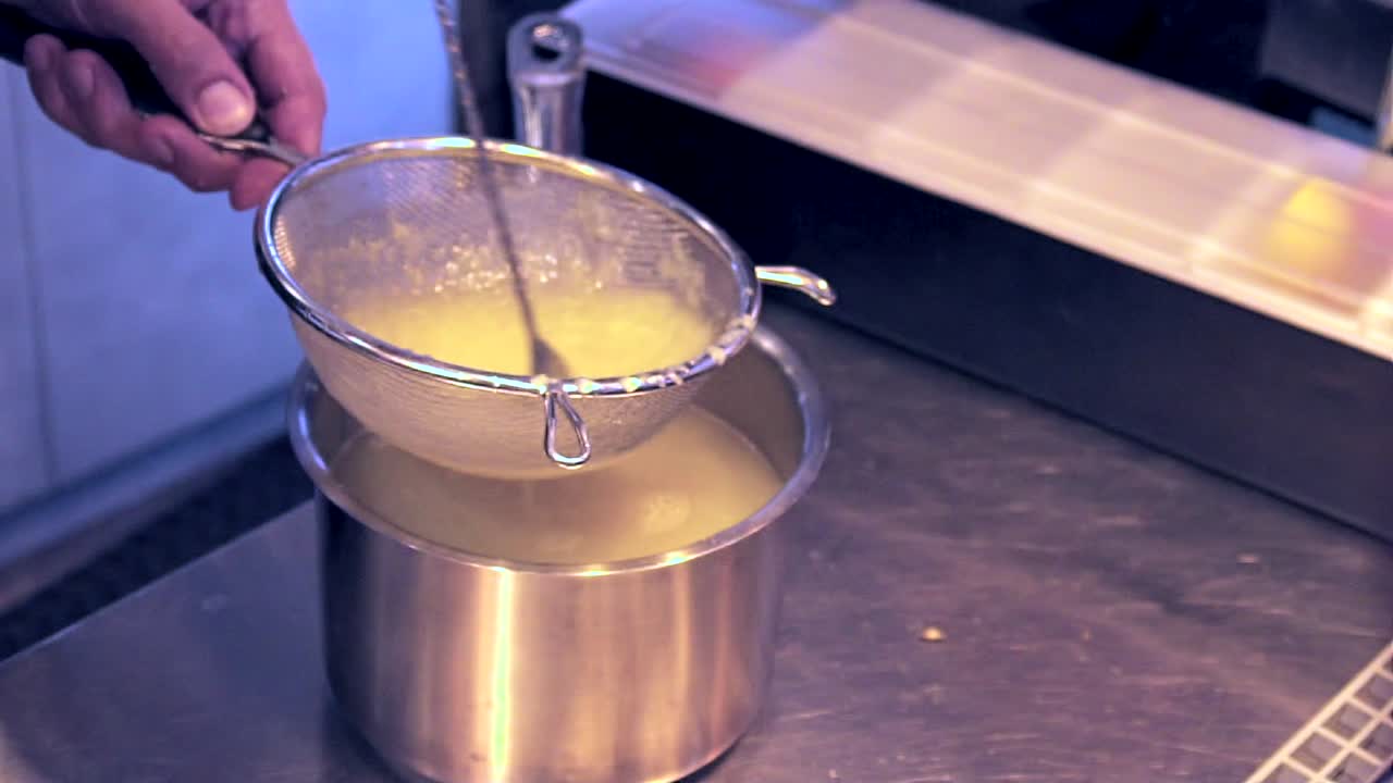 Vista laterale, primo piano sulle mani di un barista che mescola succo di limone in uno scolapasta.