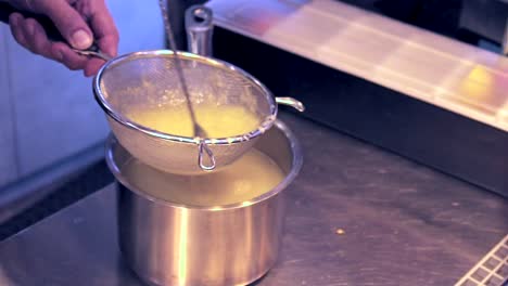 Side-view,-close-up-shot-on-hand's-of-bartender-stirring-lemon-juice-in-a-colander