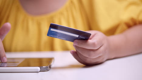 woman in yellow dress viewing images of products to make a purchase with a credit card