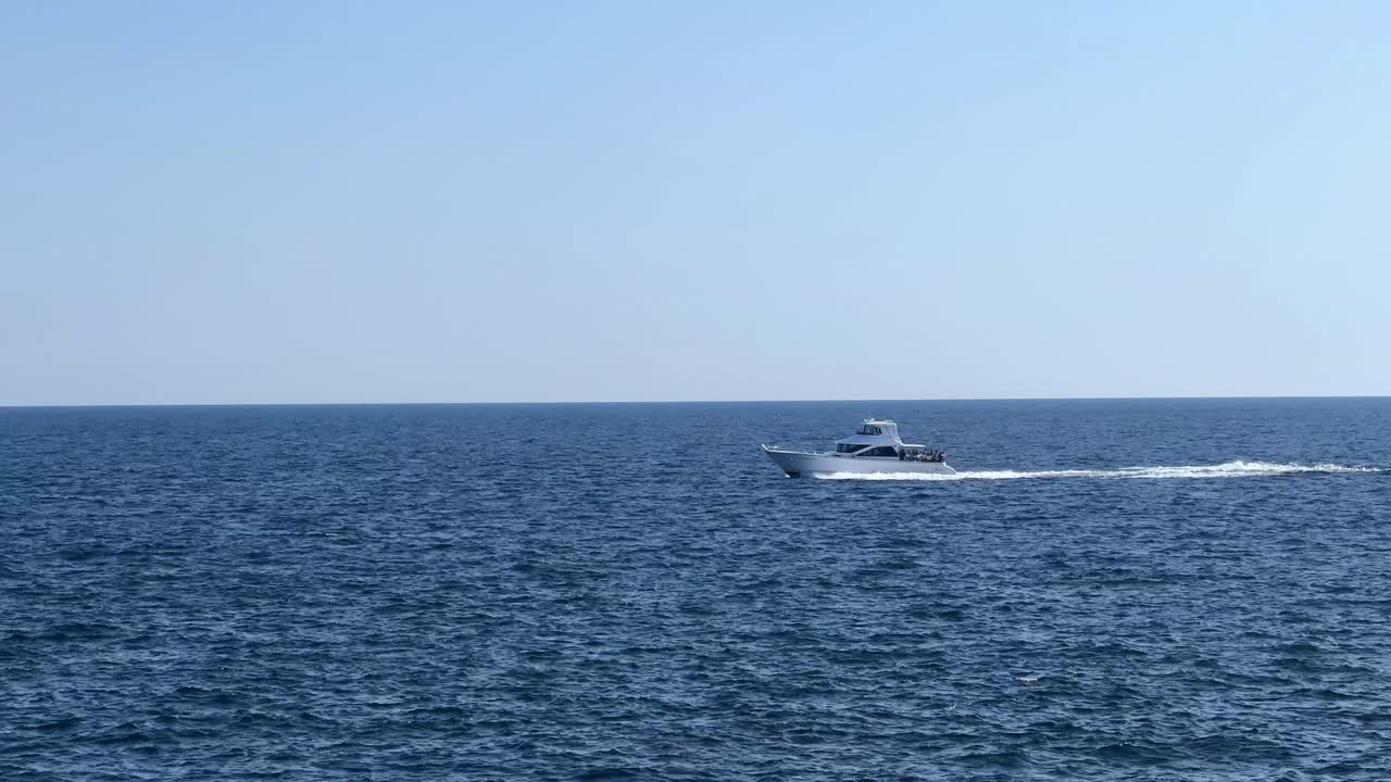 단독 보트가 은 하늘 아래 광활한 파란 바다를 가로질러 빠르게