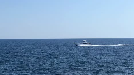 a lone boat speeds across the vast blue ocean under a clear sky