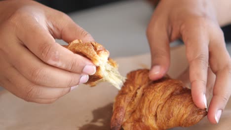 person enjoying a delicious flaky croissant