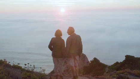 romantic senior couple standing on top of hill, admiring the beautiful landscape and kissing