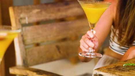 dos personas tocan vasos con cócteles amarillos vibrantes en un ambiente cálido y acogedor