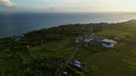 panoramic aerial view of lush tropical island coastline, roads, and town during golden hour - san andres, catanduanes, philippines