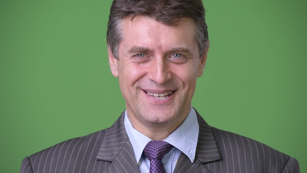 hombre de negocios maduro y guapo contra un fondo verde