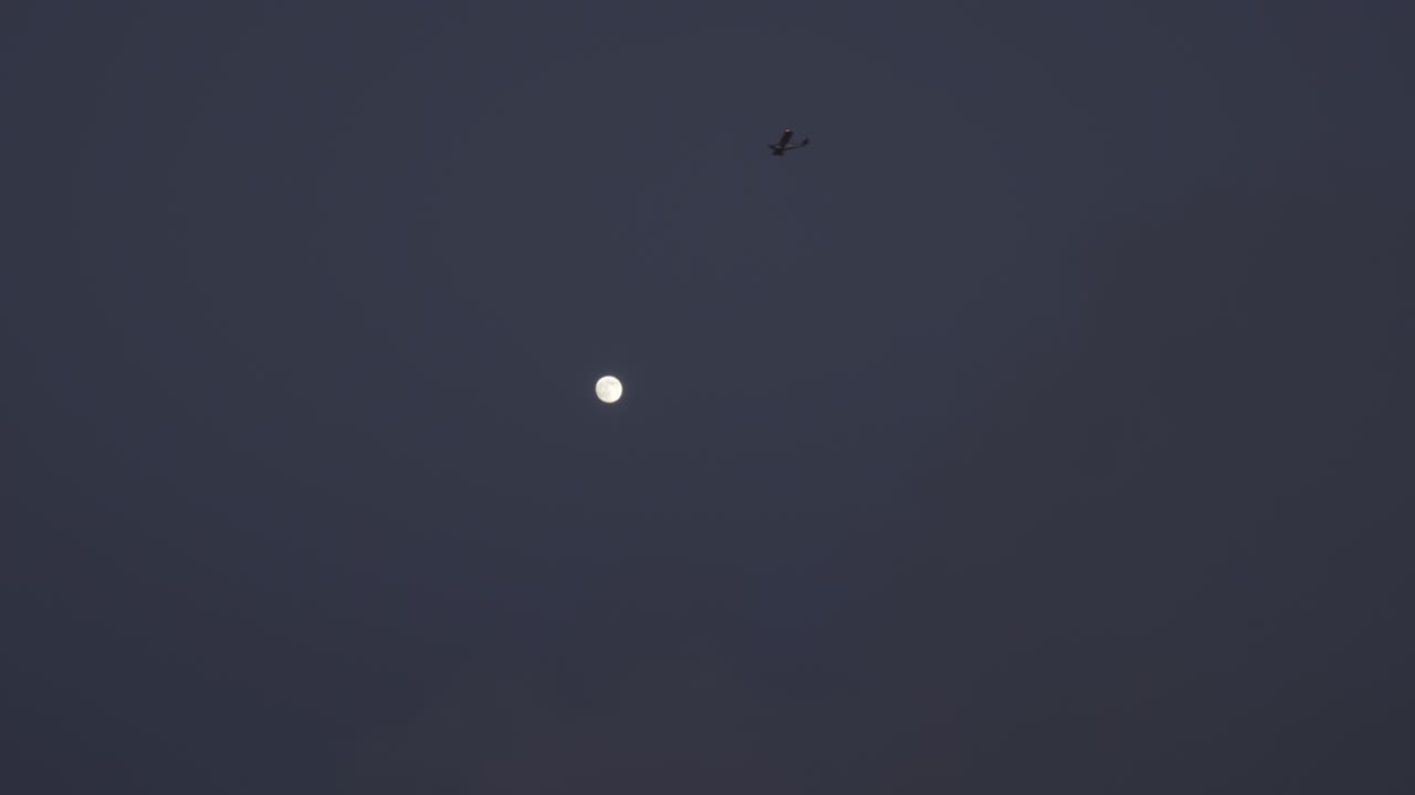 маленький самолет, летящий над полной луной.