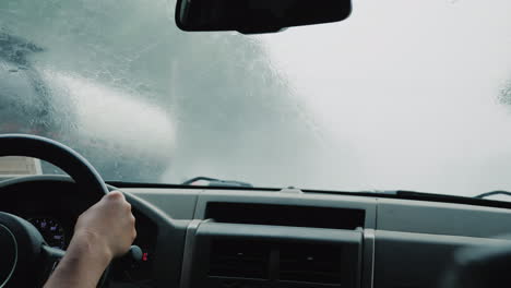 el conductor conduce el automóvil hacia una fuerte lluvia chorros de agua fluyen a lo largo del parabrisas la limpieza del parabrisas