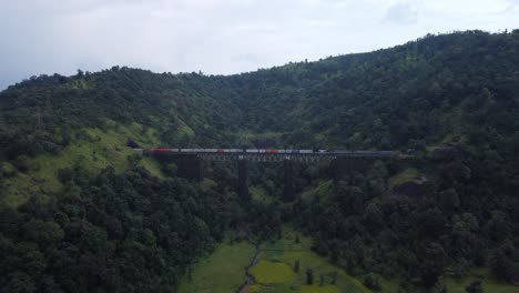 Luftaufnahme-Der-Indischen-Eisenbahnstrecke-Und-Der-Indischen-Autobahn,-Die-In-Einem-Schuss-Parallel-Verlaufen,-Während-Güterzug-Und-Lokomotive-Vorbeifahren