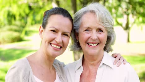 Mother-and-adult-daughter-smiling-at-camera-in-the-park