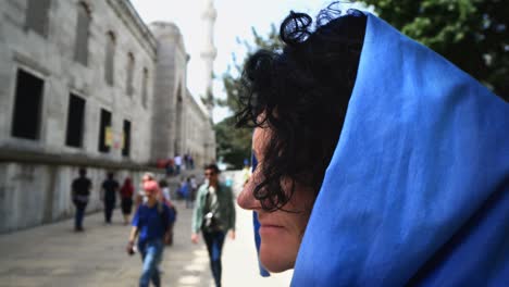 close-up portrait of a happy young muslim woman in a blue scarf at visit of sultanahmed mosque. summer travel, exchange student