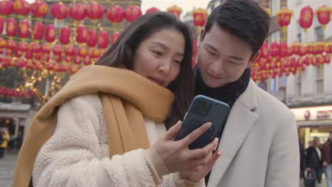 Joven-Pareja-Asiática-De-Vacaciones-Posando-Para-Selfie-En-Teléfono-Móvil-En-Chinatown,-Londres,-Reino-Unido-4