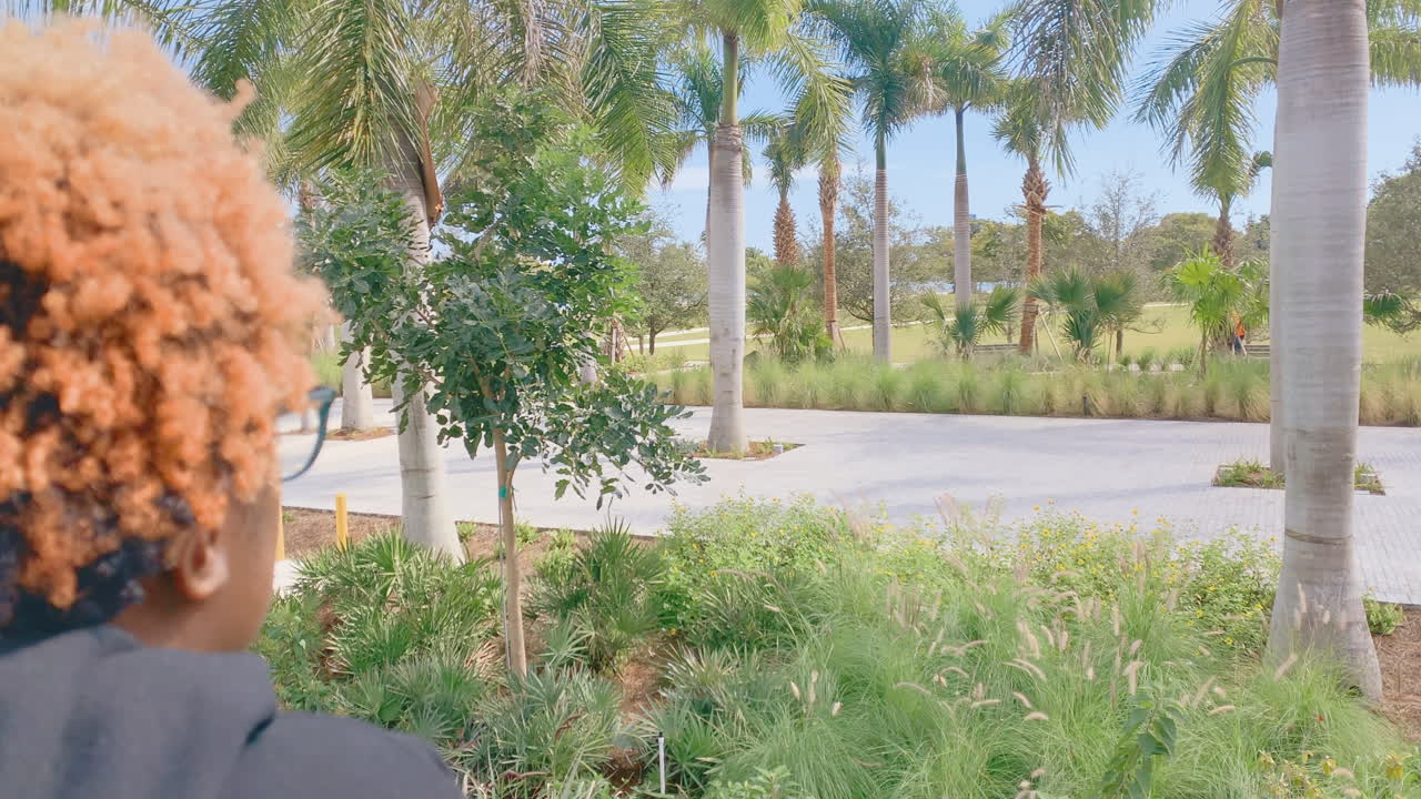 공원에서 사람들을 지켜보는 색 ⁇ 의 머리카락을 가진 아프리카계 미국인 여성