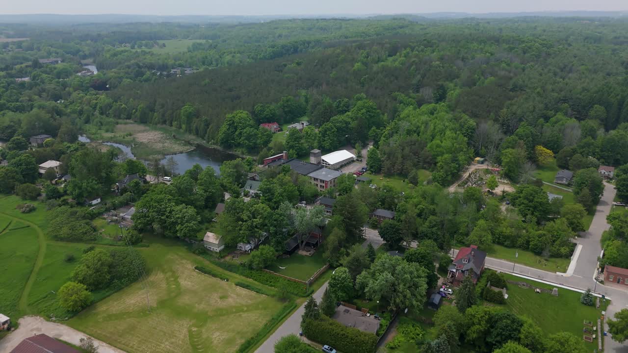 Drone flyover of Alton Mill surrounded by trees in Caledon, Ontario, Canada in foggy summer light