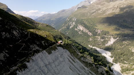 Aerial-view-of-a-mountain-refuge-on-top-of-the-mountain-surrounded-by-the-forest-in-Zinal,-Switzerland