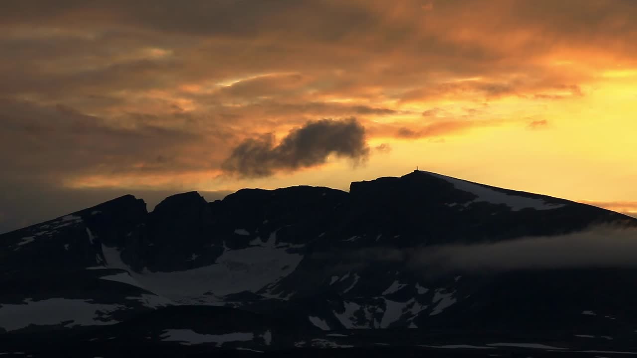 cielo del atardecer y nubes coloridas sobre el pico de la montaña snohetta