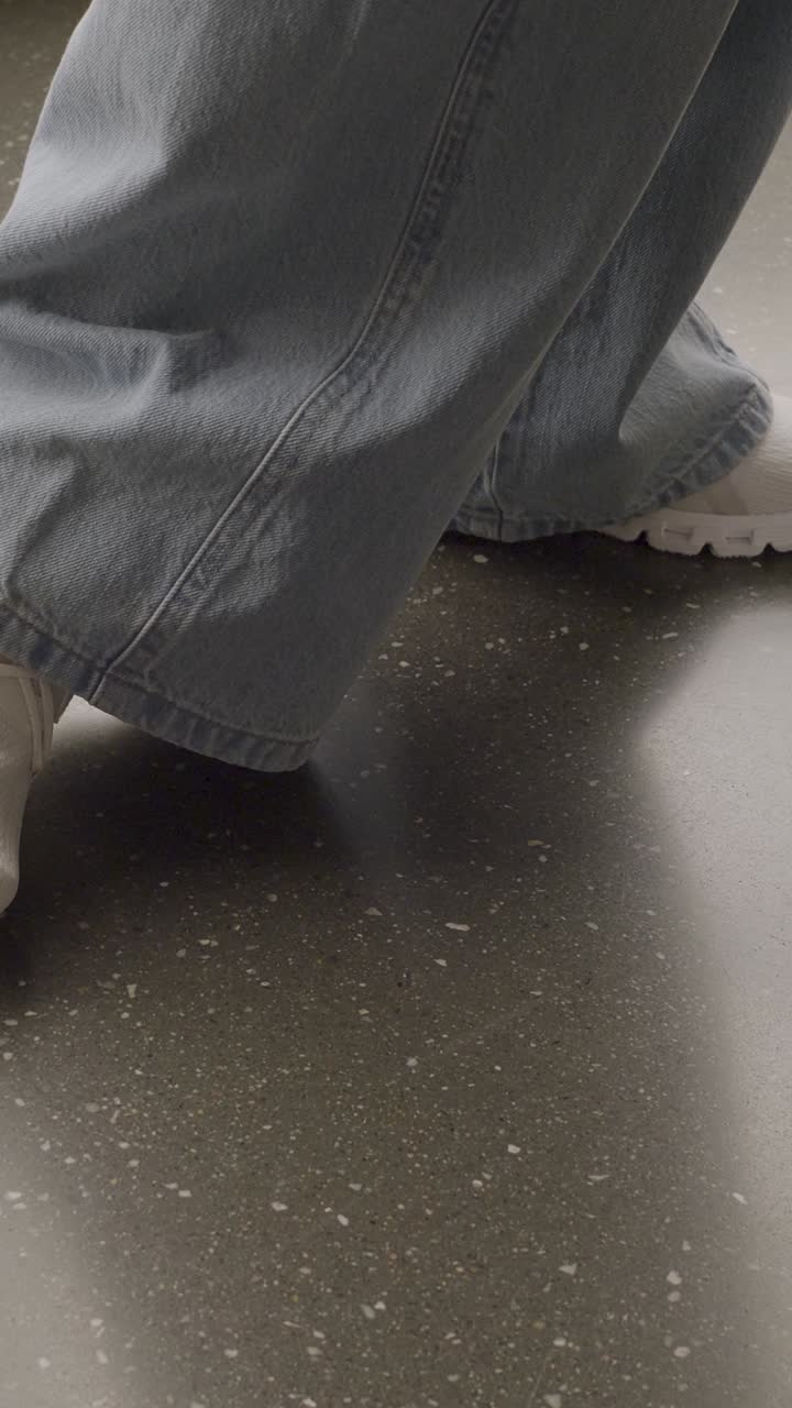 Person in denim jeans standing indoors on a shiny floor