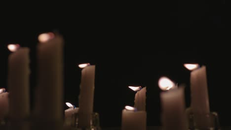 An-extreme-close-up-of-white-candles-lit-with-a-black-background-in-slow-motion