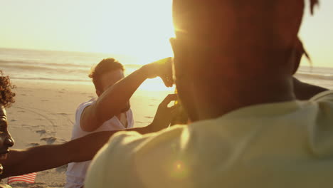 amigos adultos jóvenes bebiendo en una playa al atardecer 4k