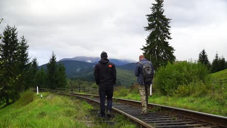 Dos-Hombres-Van-En-Los-Ferrocarriles-Frente-A-Las-Montañas