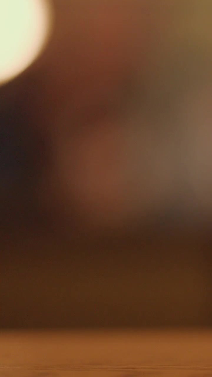 Video morbido e sfocato di un tavolo di legno con luci bokeh calde e soffuse sullo sfondo. Ambientazione notturna, telecamera statica, atmosfera accogliente