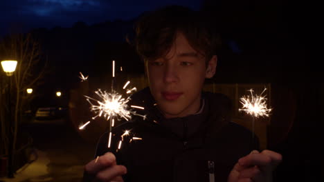 teenager with sparklers at night