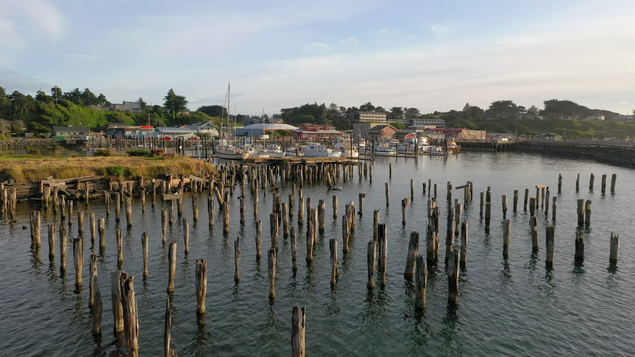 hermosa vista de los viejos postes del muelle pilotes bajo un cielo azul océano con barcos amarrados en el puerto de bandon, oregon
