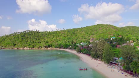 4k aerial drone push forward shot of salad beach on koh phangan in thailand with fishing boats, teal water, coral, and green jungles