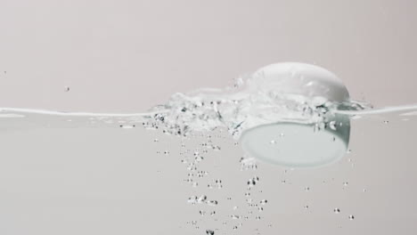 video of beauty product tub falling into water with copy space on white background