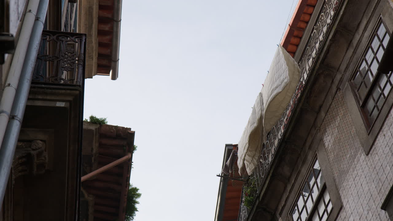 Hanging Washed Blankets Out To Dry On A Balcony Of An Old Town House In Porto, Portugal. Low Angle Shot