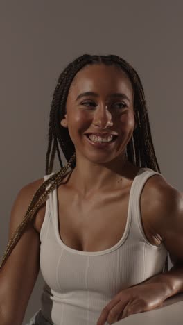 studio beauty shot of young woman with long braided hair against neutral background in profile 2