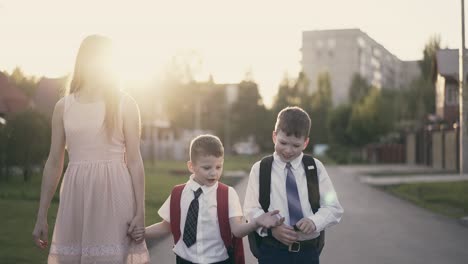 la madre va con los niños a la escuela le cuentan sobre sus éxitos ella sonríe y los elogia