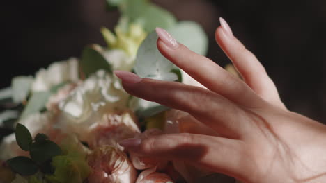 woman hand strokes fresh bouquet with rose flowers in room