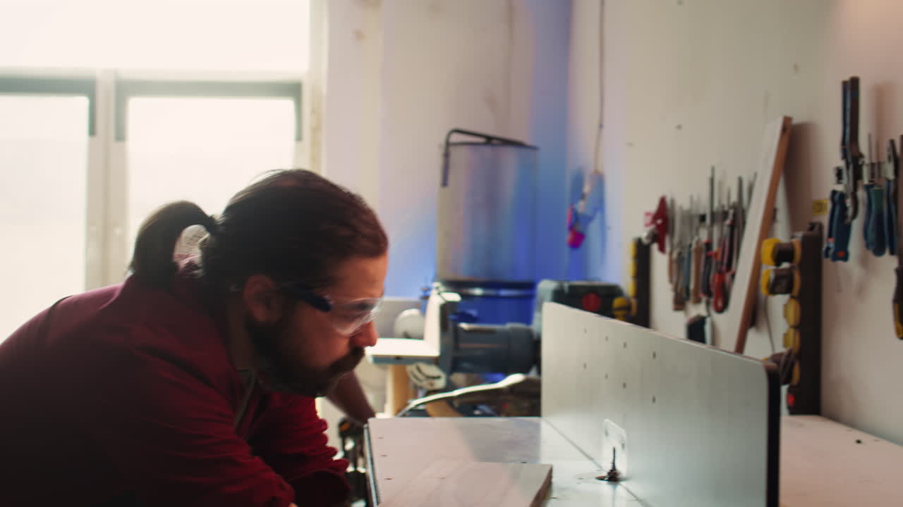 Man putting on protection gear while inserting plank in spindle moulder