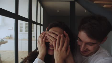 retrato de una familia joven entrando en la casa. hombre sonriente cerrando los ojos a la mujer.