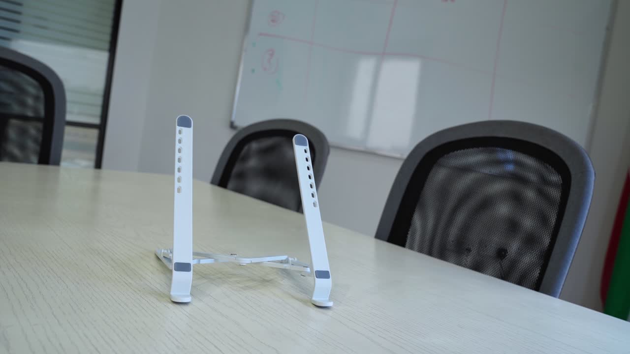 Modern office shot of foldable laptop stand held in hands—perfect for tech gear, product demos, or ergonomic workspace content.