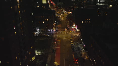 Volar-Por-Encima-De-La-Calle-Rodeada-De-Edificios-De-Varios-Pisos-En-El-Distrito-Urbano.-Escena-De-La-Ciudad-Nocturna.-Manhattan,-Ciudad-De-Nueva-York,-Estados-Unidos