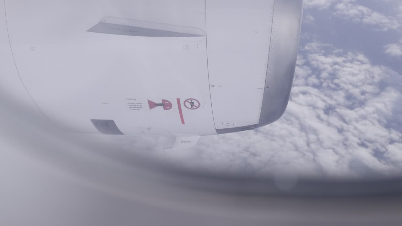 Passenger plane engine view from window, flying above clouds in daylight sky
